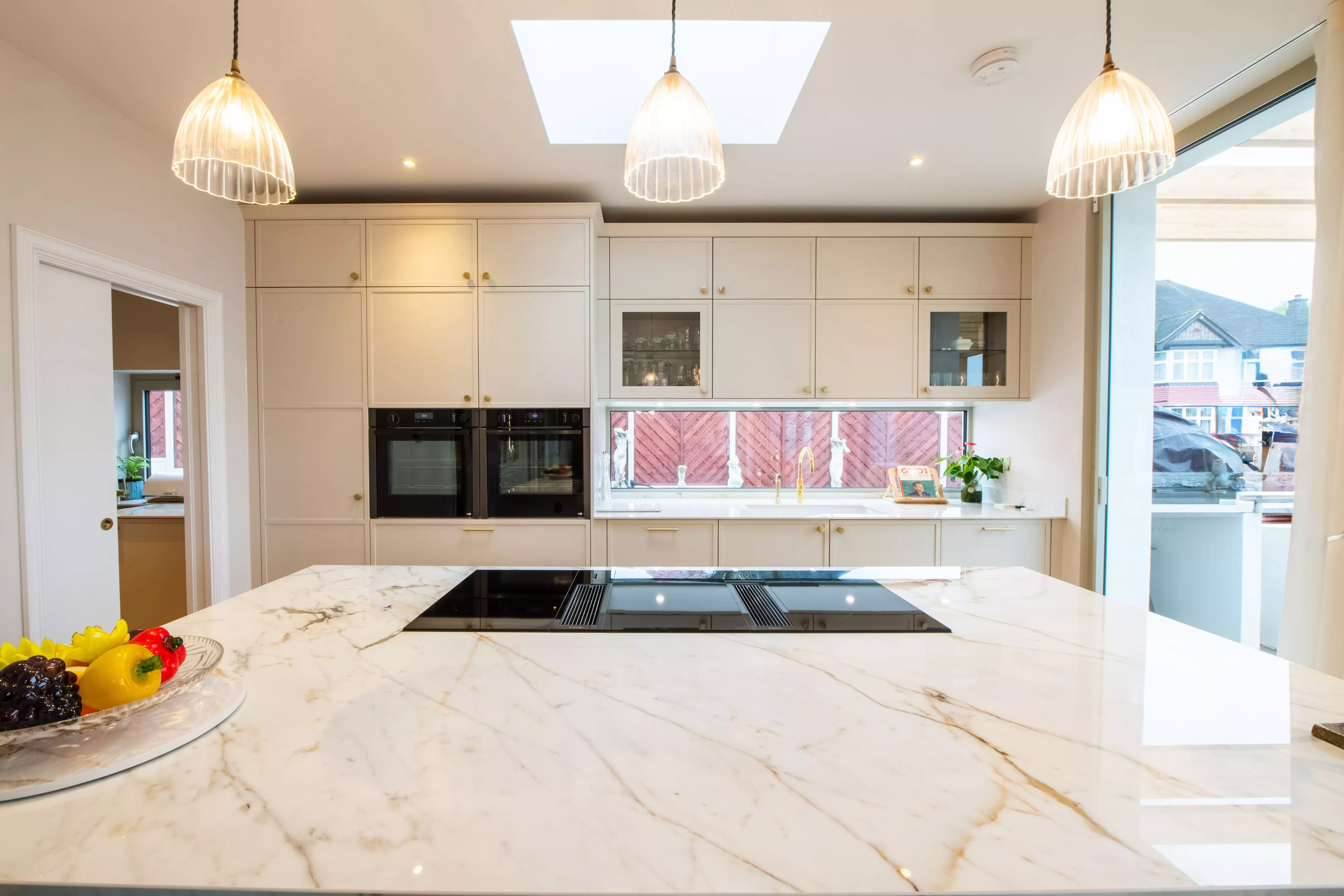 front view shaker style kitchen in white with gold accents and 3 hanging lights